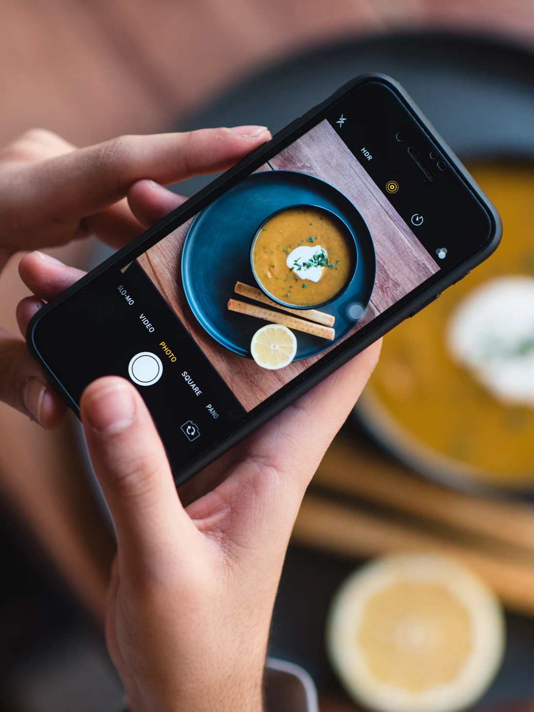 Hands holding a phone over a plate at a table
